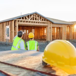 Two construction workers looking at a custom-built framed home